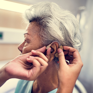 a woman being fitted for a hearing aid - representing audiology